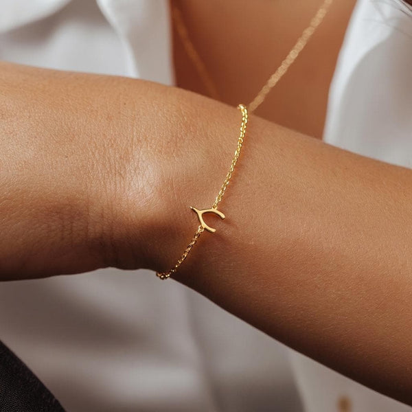 Fine gold chain bracelet with a small wishbone charm and lobster clasp