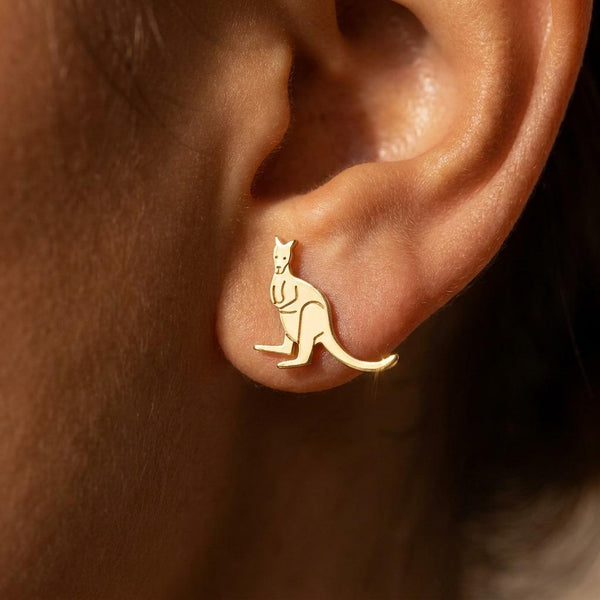 Pair of tiny gold kangaroo stud earrings with joey in pouch, white background.