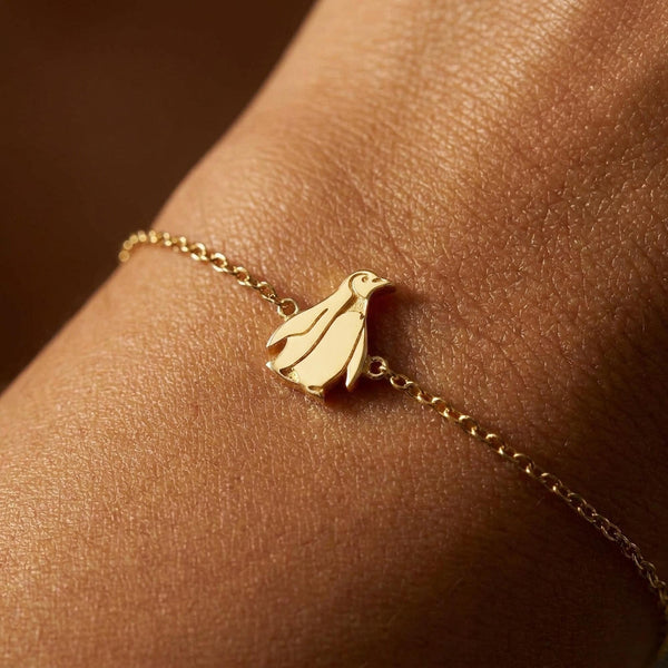 Fine gold chain bracelet with a tiny upright penguin charm