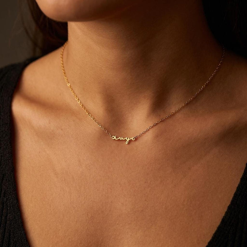 Fine gold cursive script name pendant on a dainty cable chain