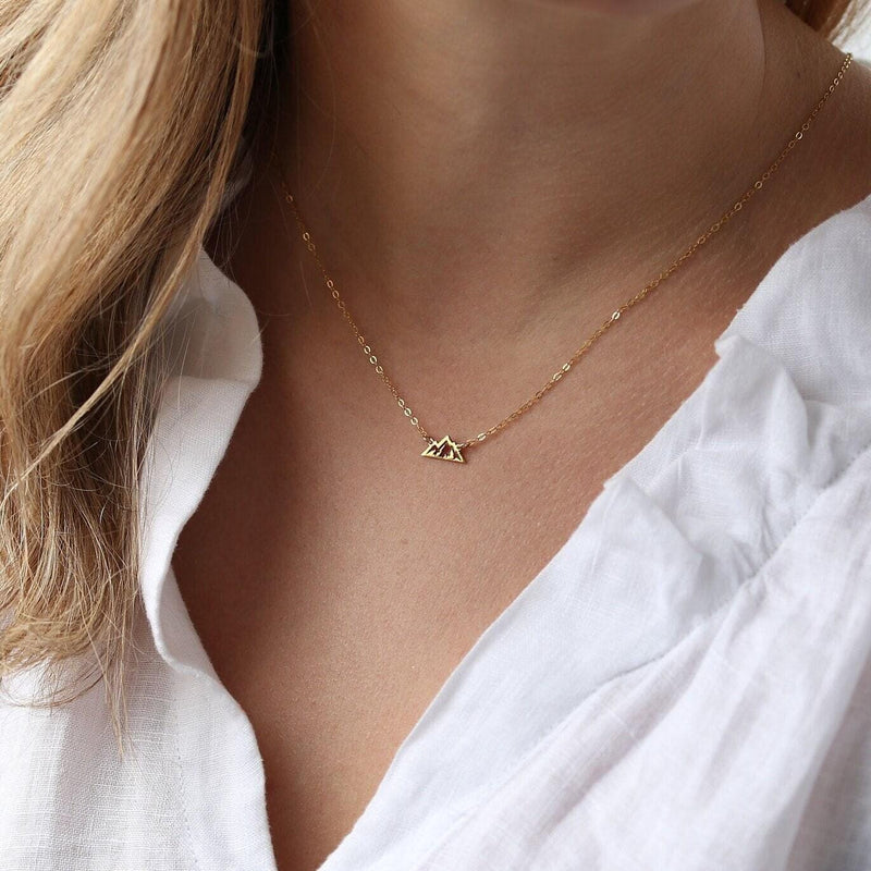 Tiny gold mountain peak pendant on a fine cable chain, shown flat on a white background