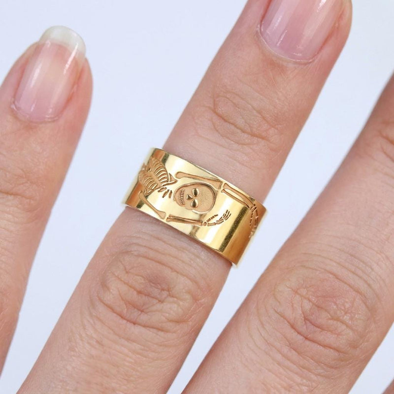 Thin gold ring with a flat skeleton figure along the band