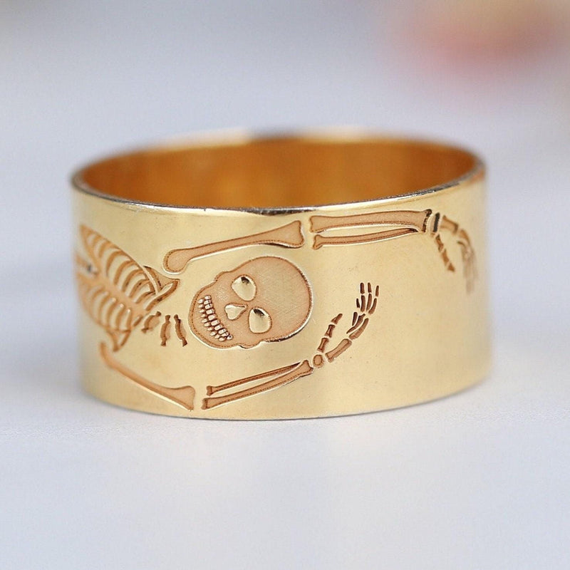Thin gold ring with a flat skeleton figure along the band (4 of 9)