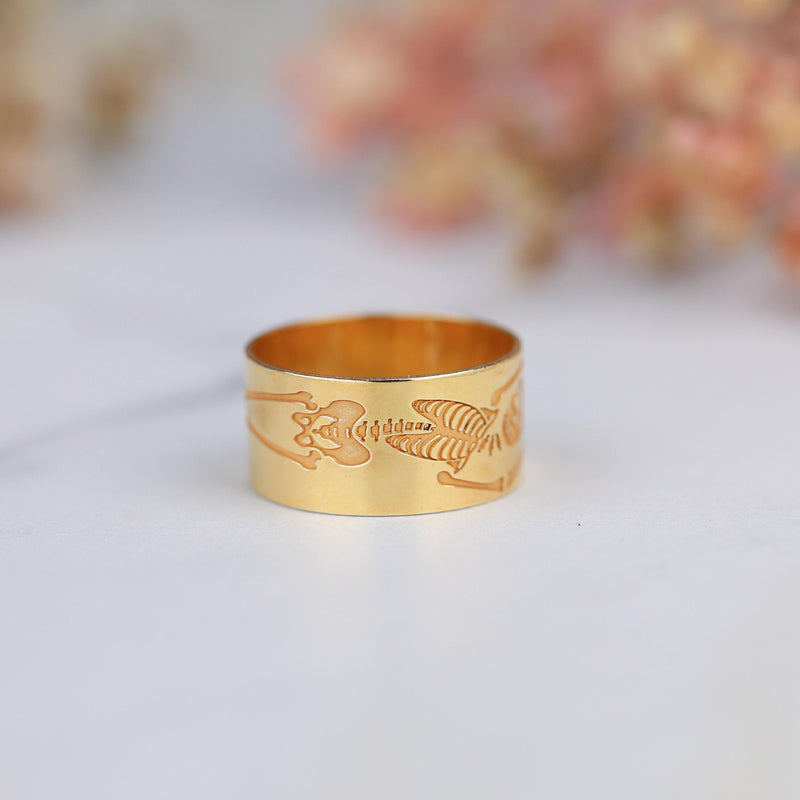Thin gold ring with a flat skeleton figure along the band (5 of 9)