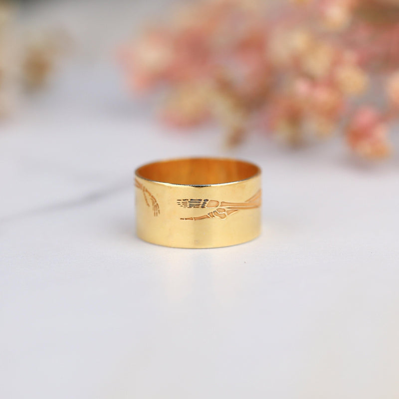 Thin gold ring with a flat skeleton figure along the band (6 of 9)