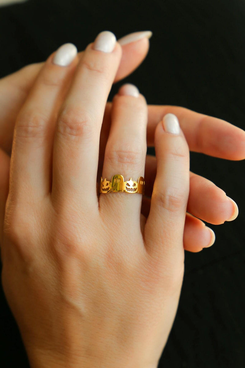 Thin gold stacking ring with a small RIP tombstone charm on the crown
