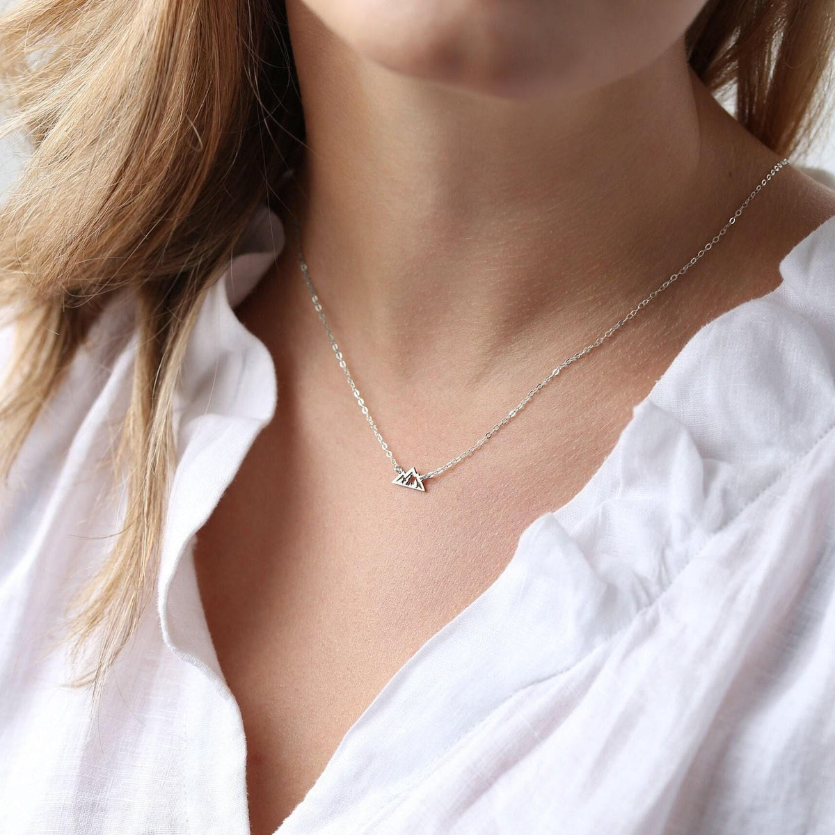 Small mountain range pendant hanging from a thin gold chain