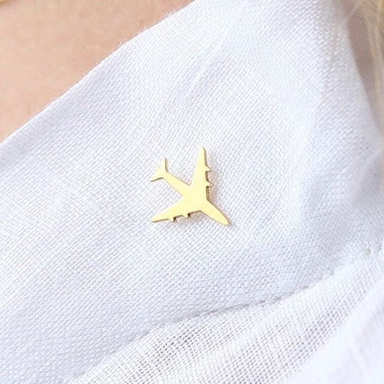 Small gold airplane lapel pin shown at an angle on a white background