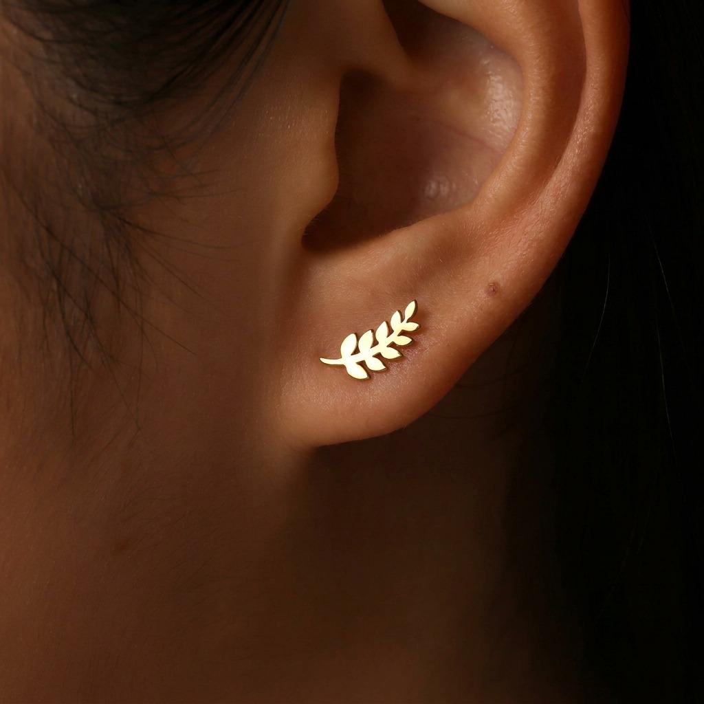 Slender gold olive branch stud earrings with leaves along a thin sprig