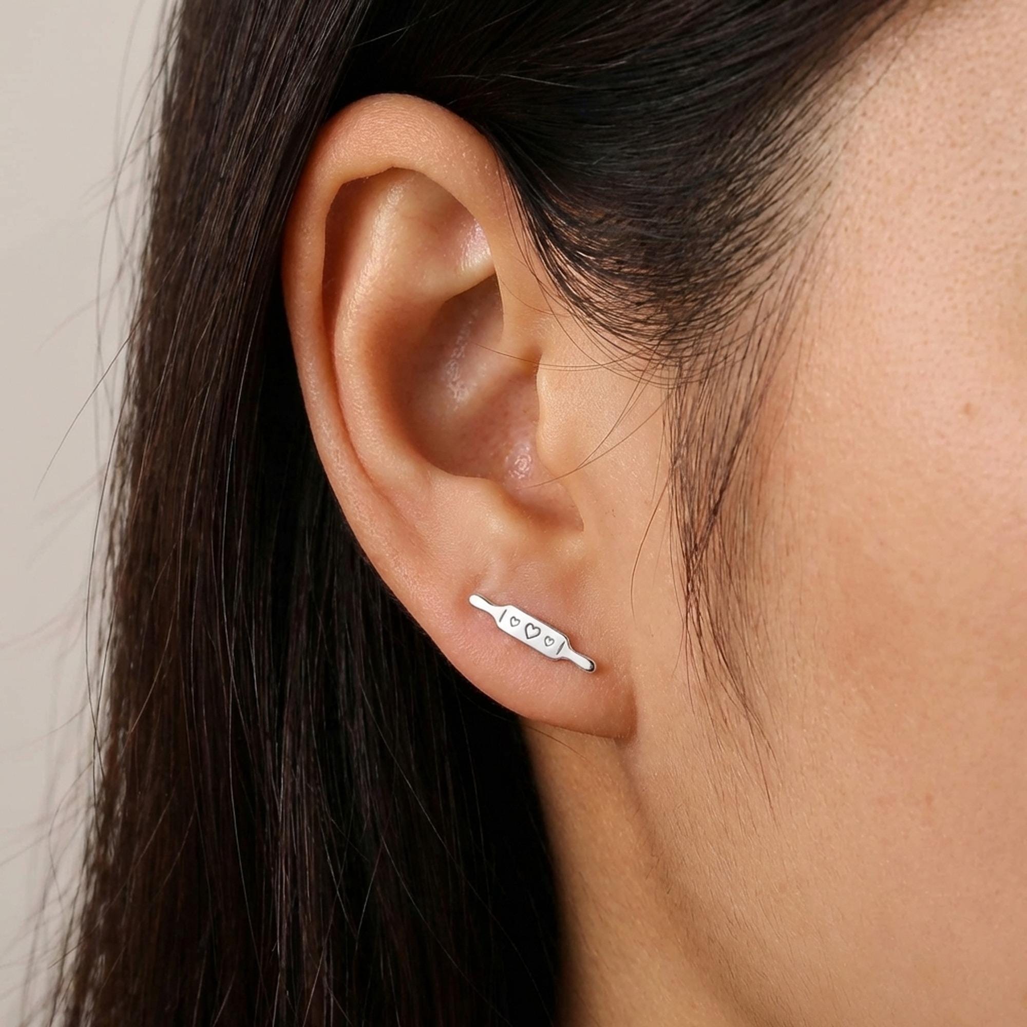 Pair of slim gold rolling pin stud earrings lying horizontally with two handles (2 of 6)