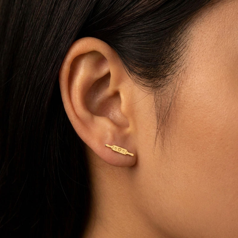 Pair of slim gold rolling pin stud earrings lying horizontally with two handles (3 of 6)
