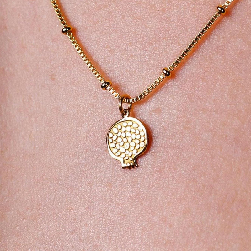 Gold cut pomegranate pendant showing seeds, on a fine cable chain