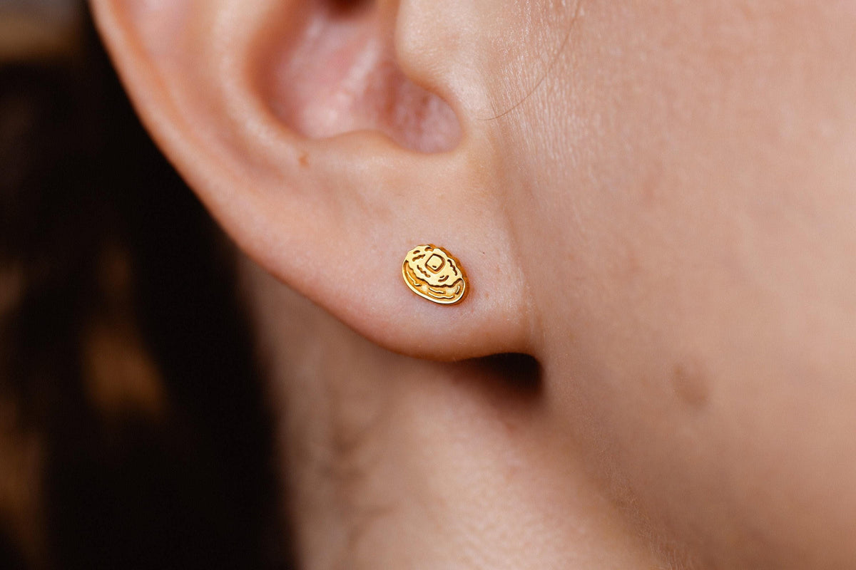 Pair of tiny gold baked potato stud earrings split open with butter on top
