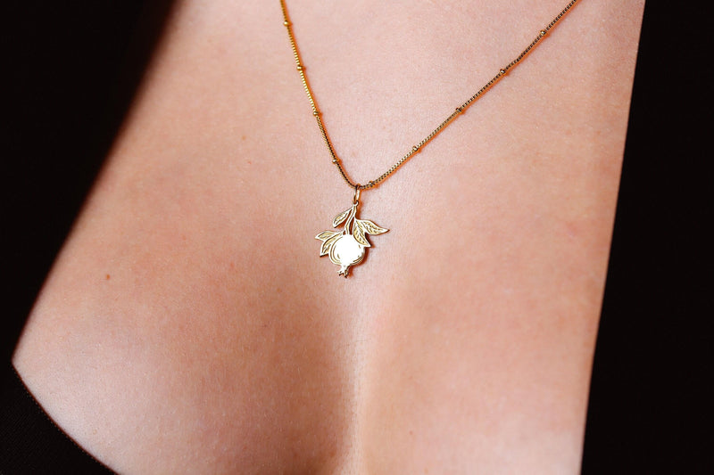 Small gold pomegranate pendant with crown top on a fine chain