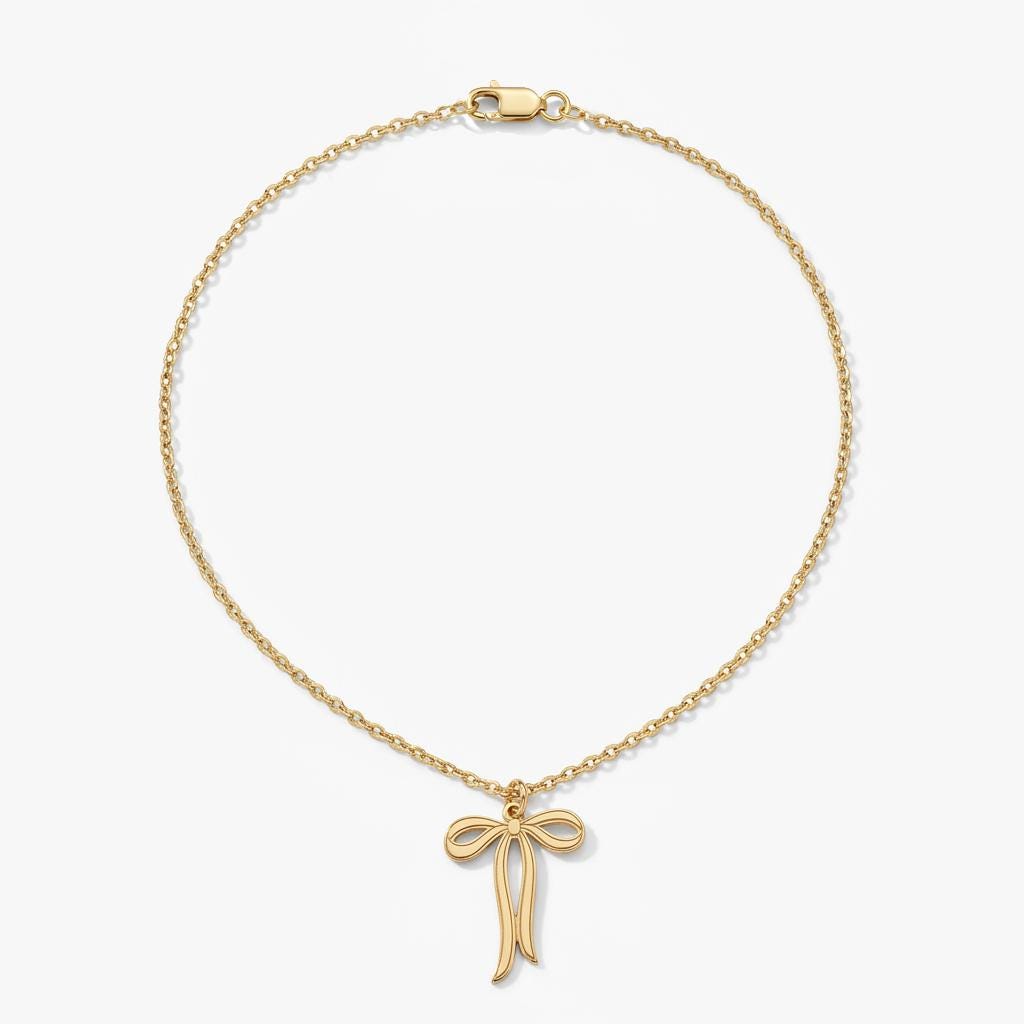 Slim gold ribbon bow pendant with trailing tails on a fine chain, white background.
