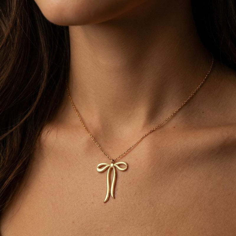 Slim gold ribbon bow pendant with trailing tails on a fine chain, white background. (4 of 9)