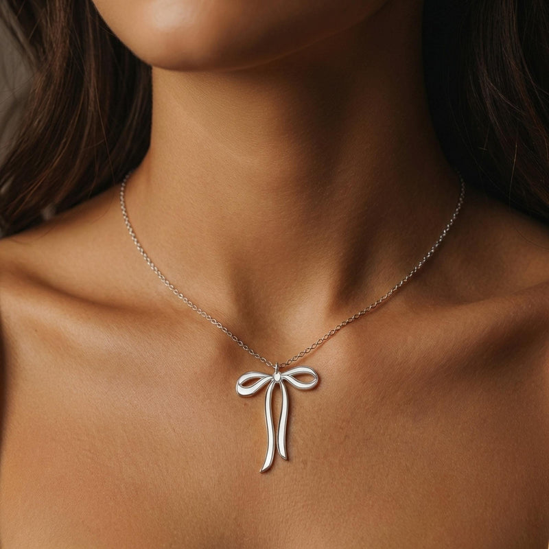Slim gold ribbon bow pendant with trailing tails on a fine chain, white background. (5 of 9)