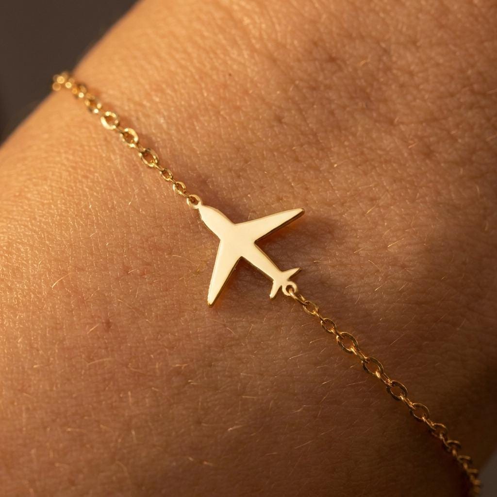 Dainty gold airplane charm on a fine chain bracelet with lobster clasp