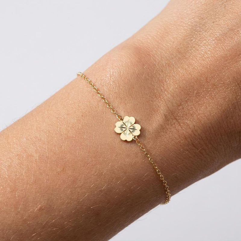 Fine chain bracelet with a flat gold four leaf clover charm.
