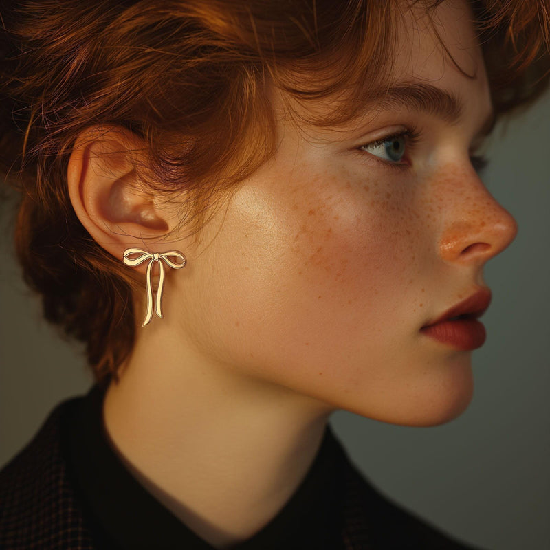 Pair of gold ribbon bow stud earrings shown flat on a white background. (10 of 10)