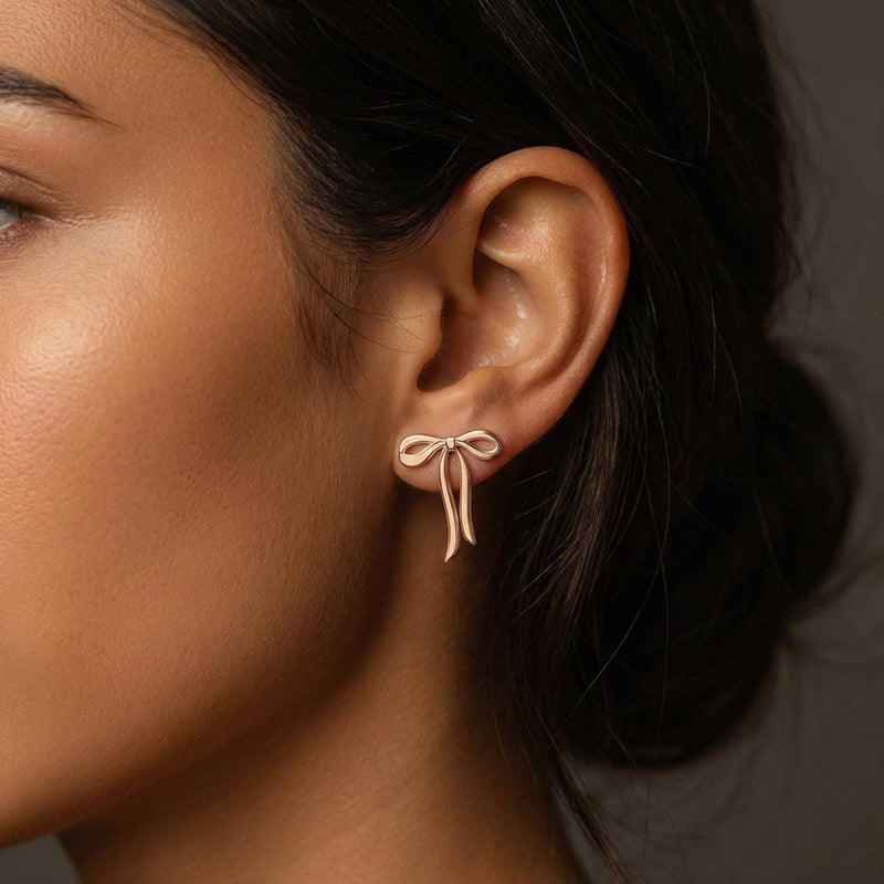 Pair of gold ribbon bow stud earrings shown flat on a white background. (4 of 10)