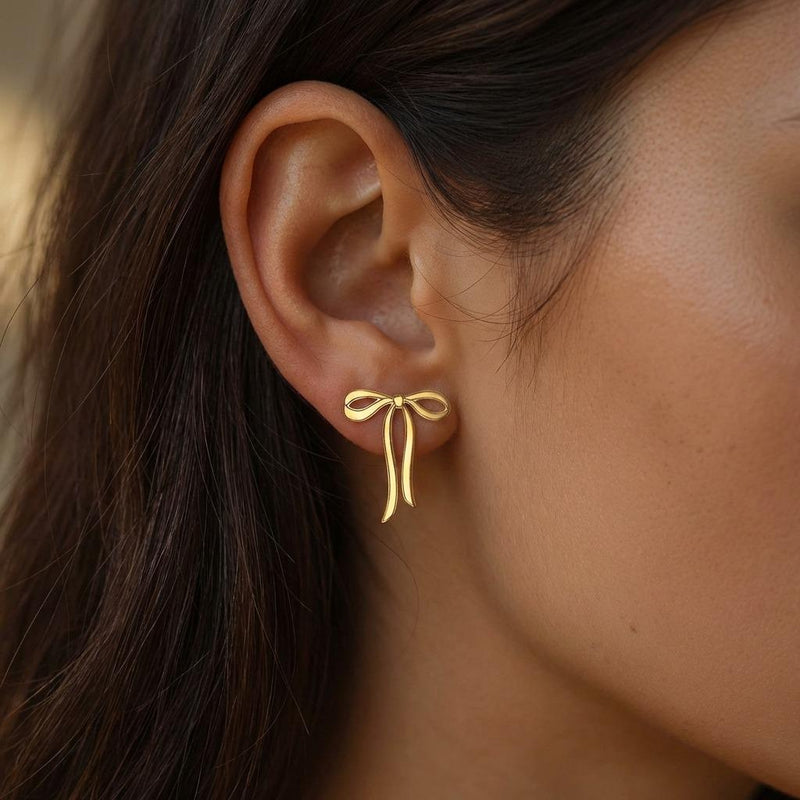 Pair of gold ribbon bow stud earrings shown flat on a white background. (5 of 10)