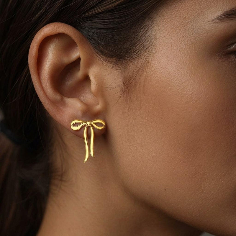 Pair of gold ribbon bow stud earrings shown flat on a white background. (6 of 10)