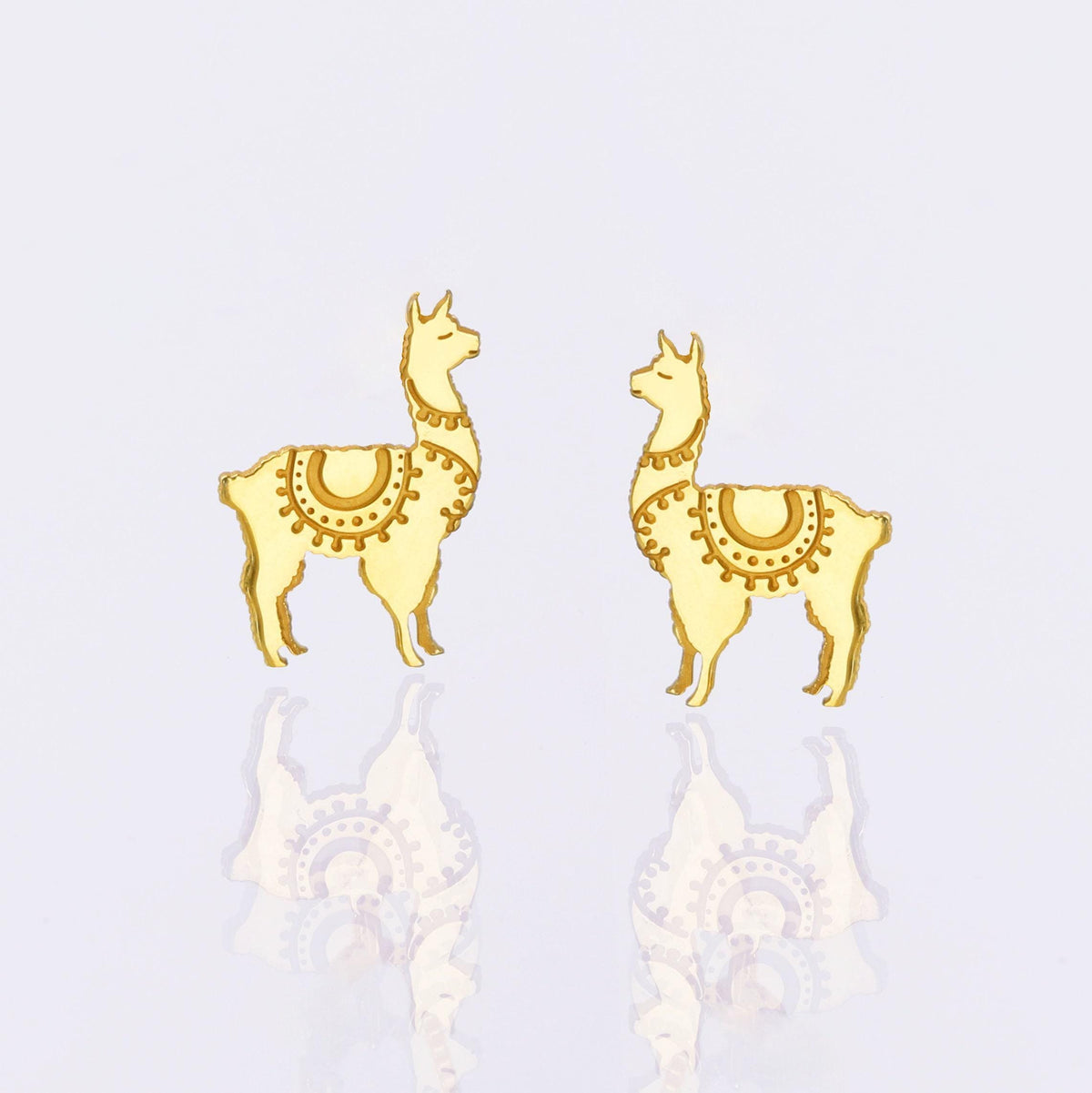 Pair of tiny gold llama stud earrings with tufted heads, shown on white