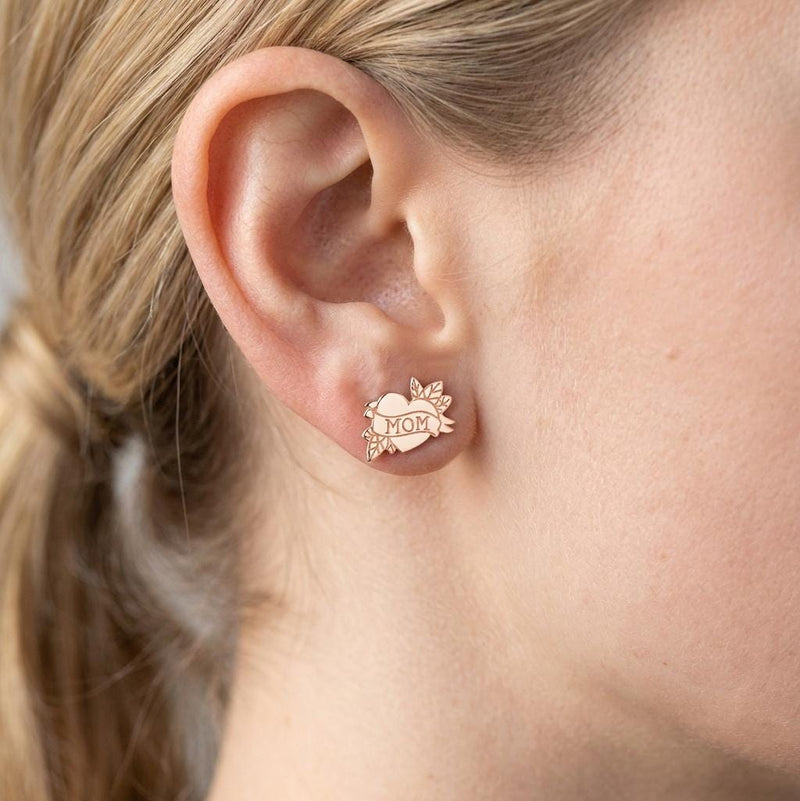 Pair of gold stud earrings shaped like a tattoo heart with a MOM banner (2 of 9)