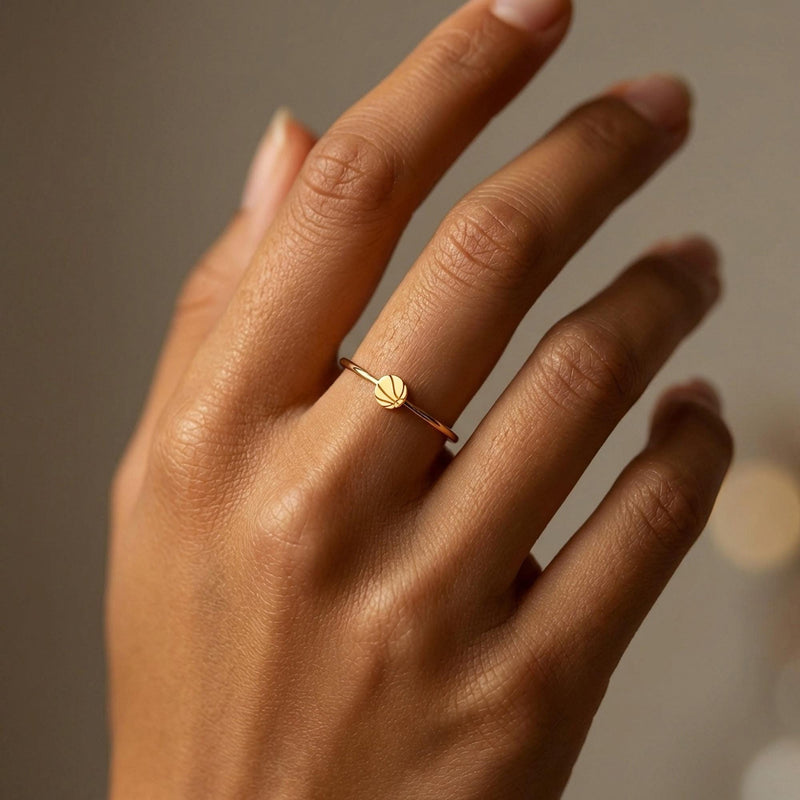 Thin gold ring with a small basketball charm showing seam lines