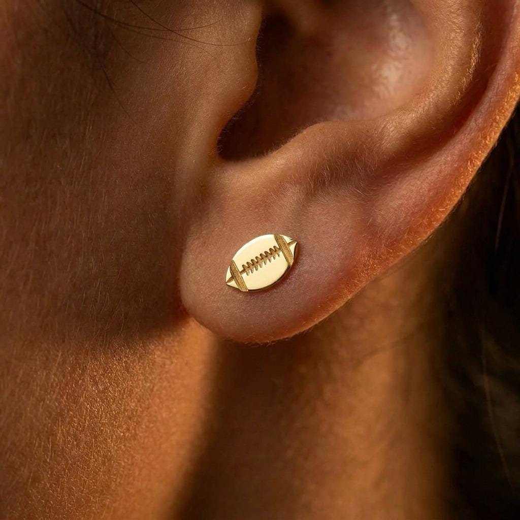 Pair of small gold football stud earrings with cut in laces