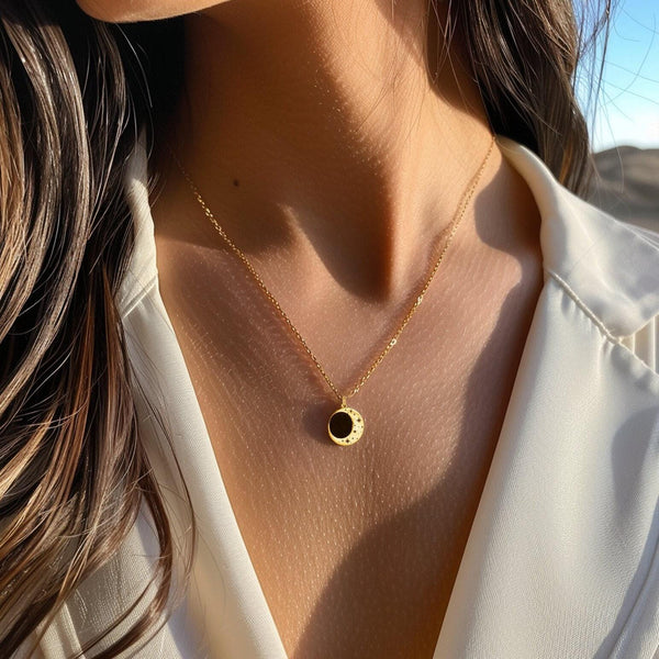 Round gold eclipse pendant with a bright outer ring on a fine chain