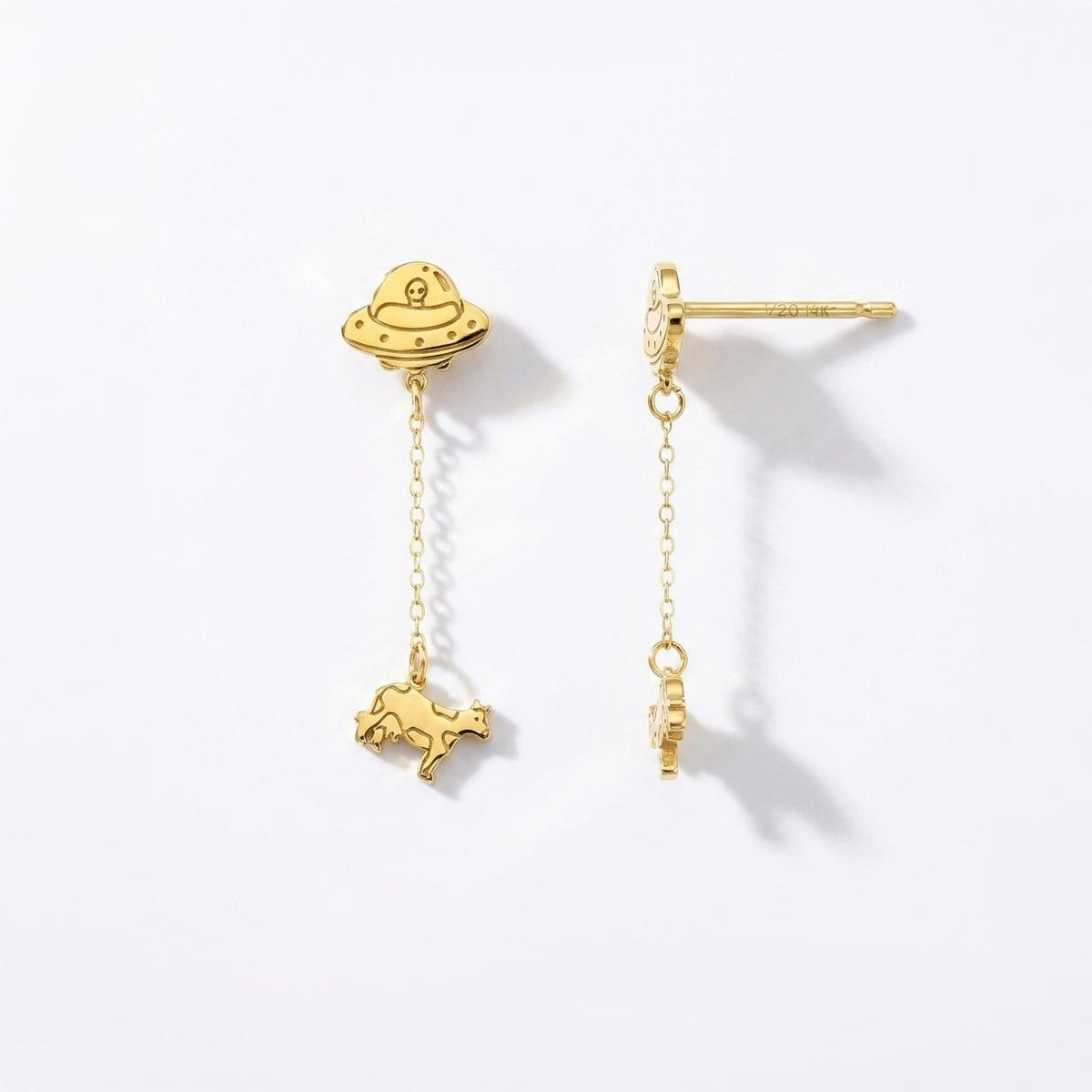 Tiny gold stud earrings showing a UFO beaming up a small cow