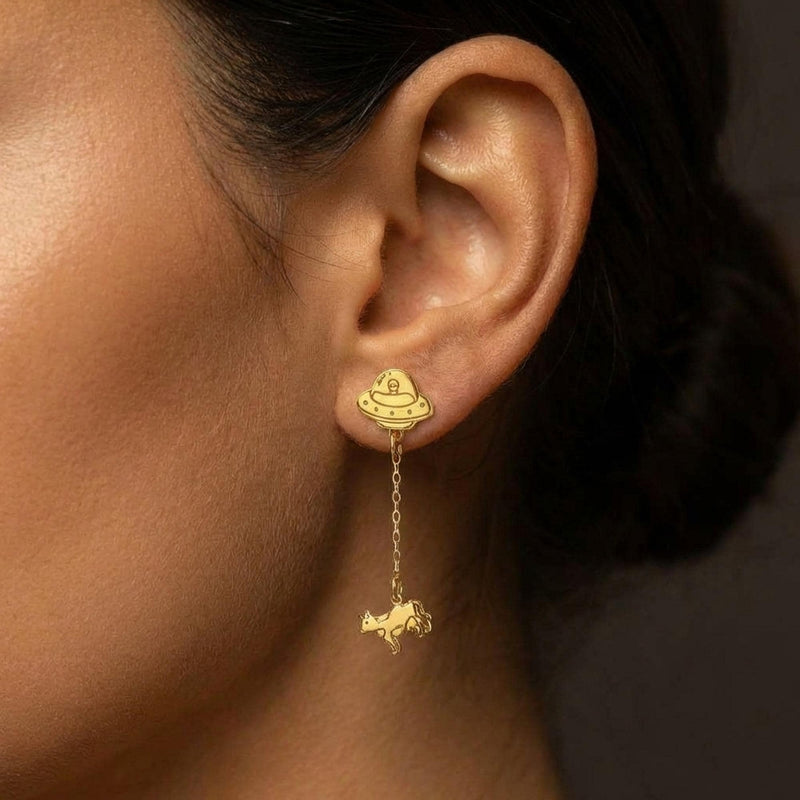 Tiny gold stud earrings showing a UFO beaming up a small cow (7 of 13)