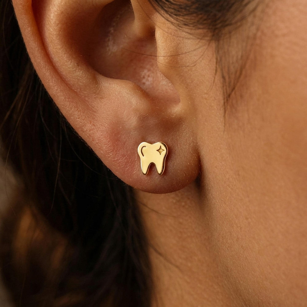 Pair of small gold tooth stud earrings photographed on a white background.