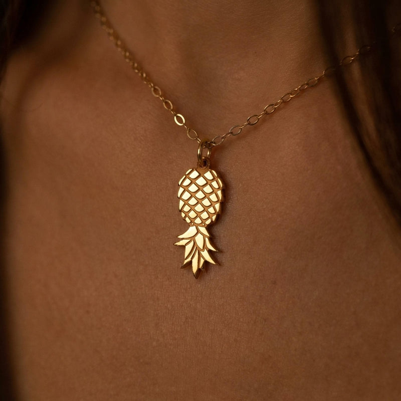 Fine gold chain necklace with a small pineapple pendant hanging point down
