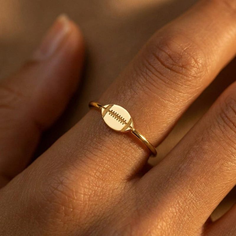 Gold ring with a small football charm with cut laces set flat on a thin band (2 of 8)