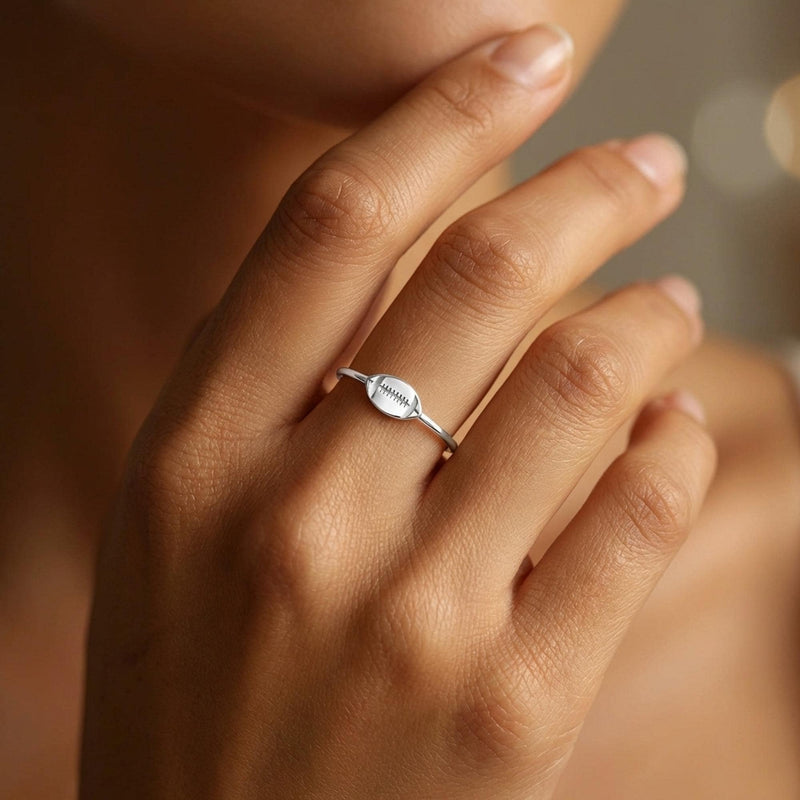 Gold ring with a small football charm with cut laces set flat on a thin band (3 of 8)