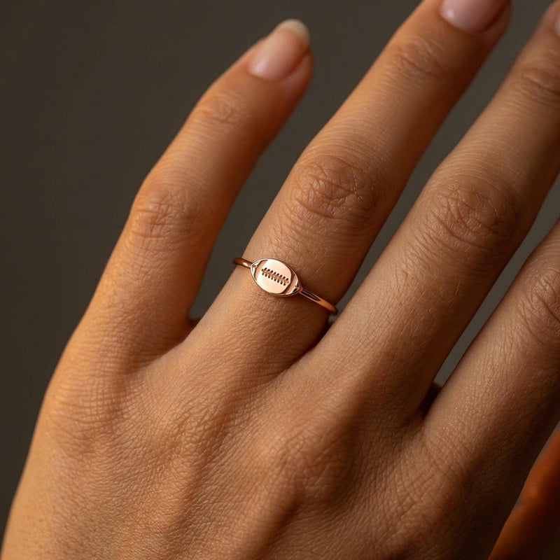 Gold ring with a small football charm with cut laces set flat on a thin band (4 of 8)