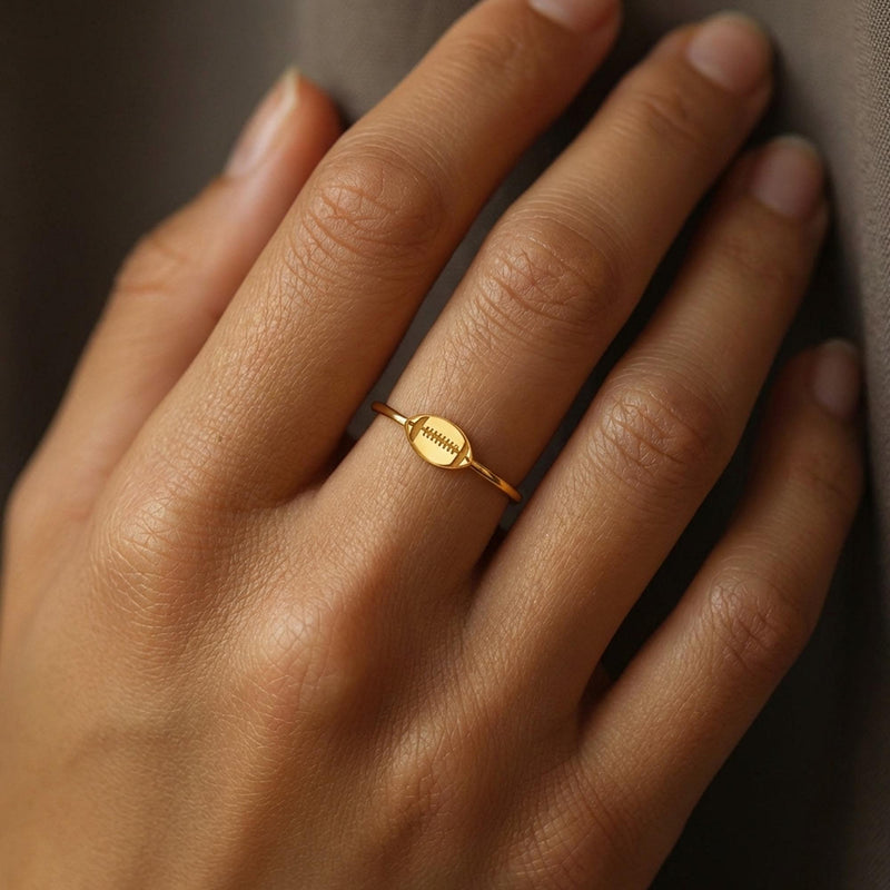 Gold ring with a small football charm with cut laces set flat on a thin band (5 of 8)