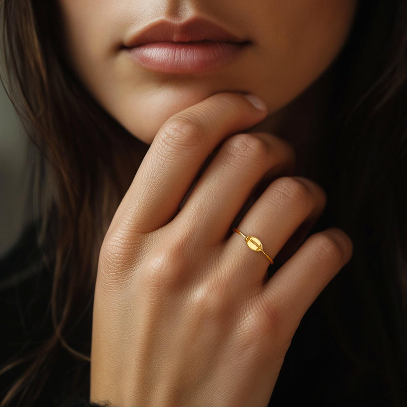 Gold ring with a small football charm with cut laces set flat on a thin band (6 of 8)