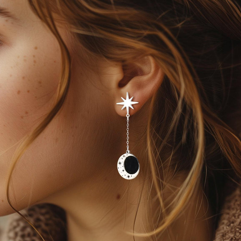 Gold crescent moon earrings with a small star hanging below, shown as a pair
