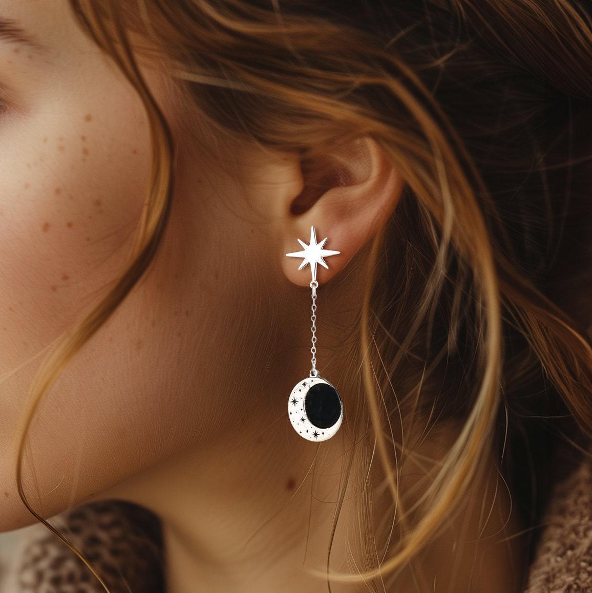 Gold crescent moon earrings with a small star hanging below, shown as a pair