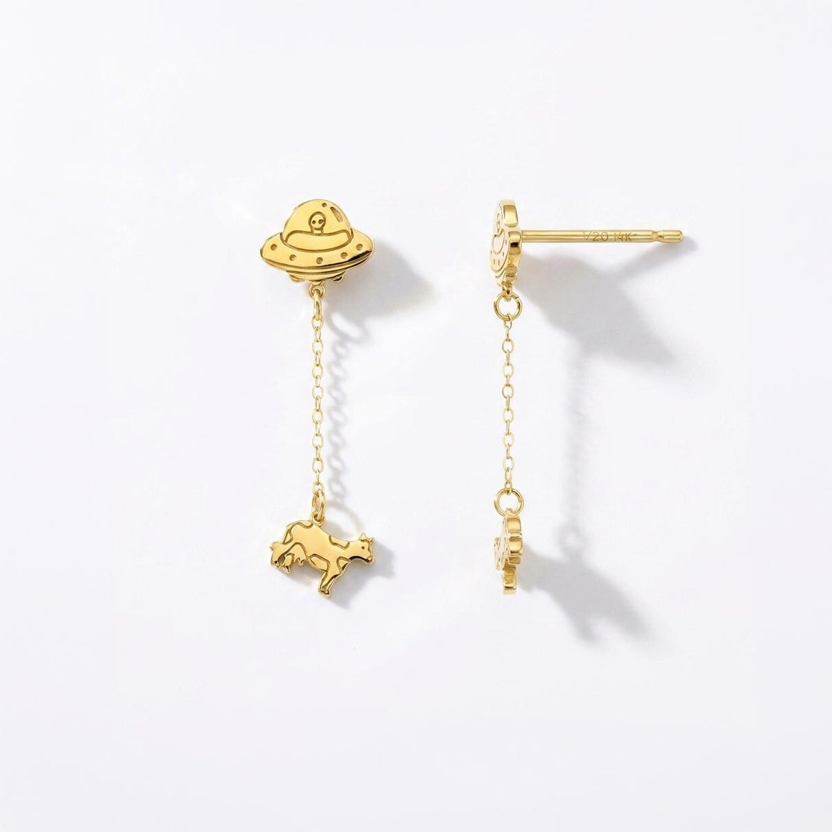 Pair of gold drop earrings showing a flying saucer beaming up a tiny cow