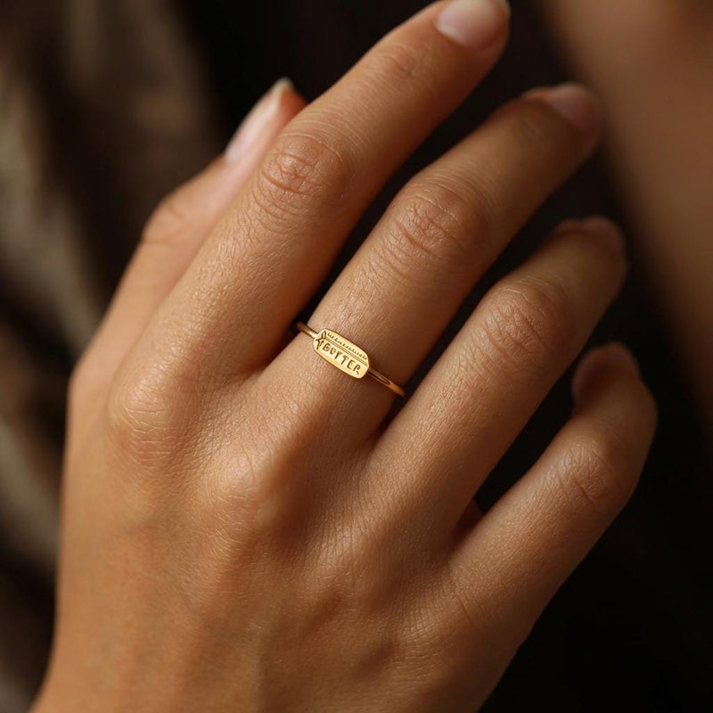 Gold ring with a small butter stick charm sitting flat on a thin round band (2 of 10)