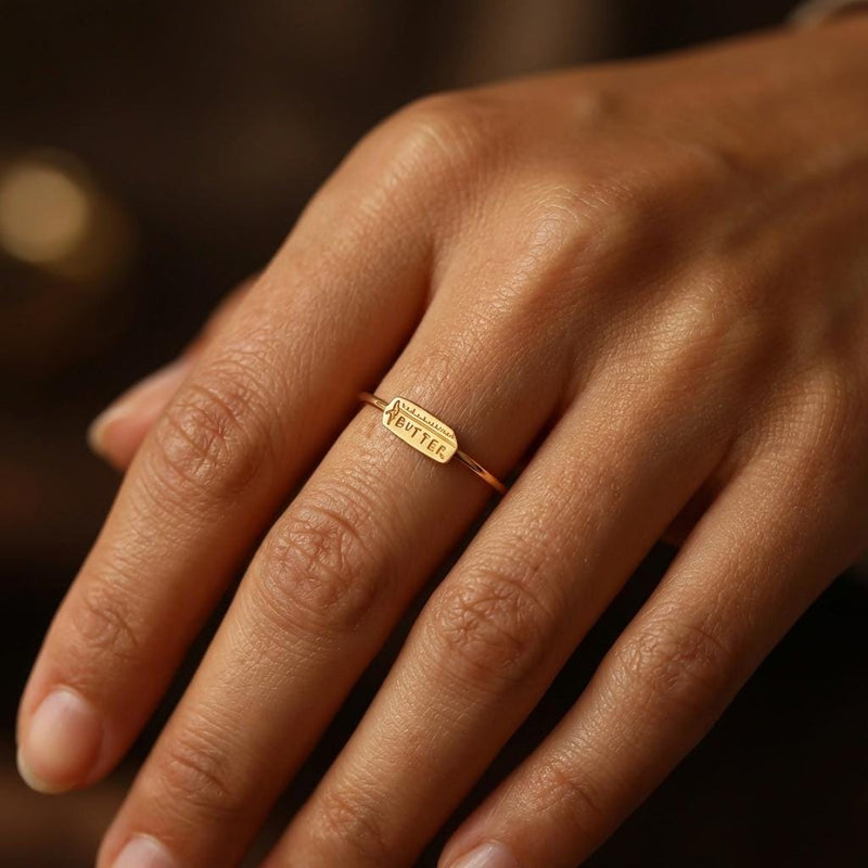 Gold ring with a small butter stick charm sitting flat on a thin round band (3 of 10)