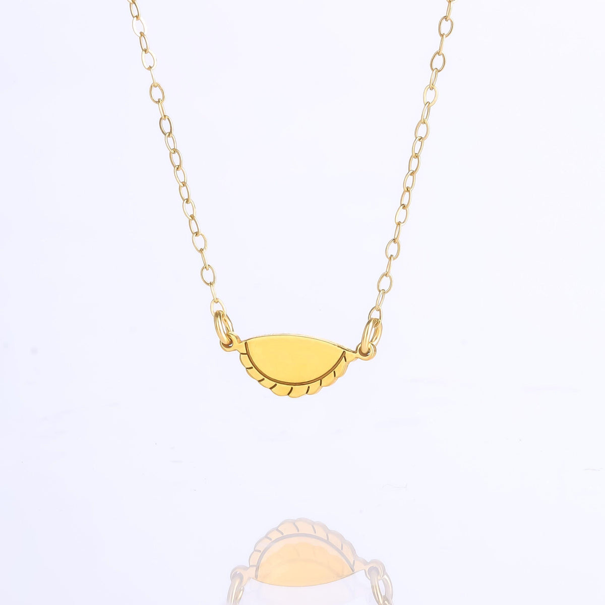 Gold empanada pendant with a crimped edge on a fine cable chain.