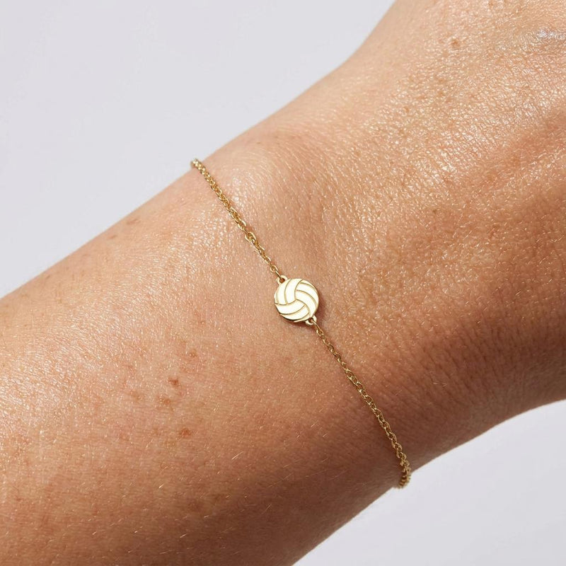Thin gold chain bracelet with a small volleyball charm with curved panels