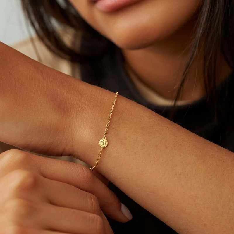 Thin gold chain bracelet with a small volleyball charm with curved panels (10 of 11)