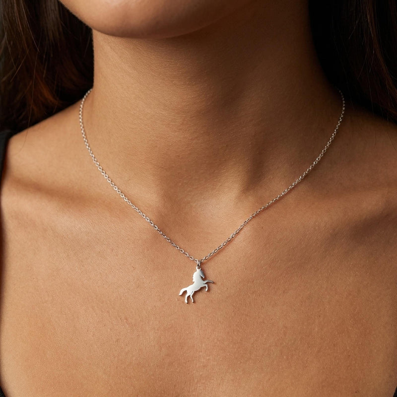 Fine gold chain necklace with a small running horse pendant on a plain background (3 of 12)